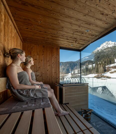 Zwei Frauen in der Sauna mit Blick auf den Schnee